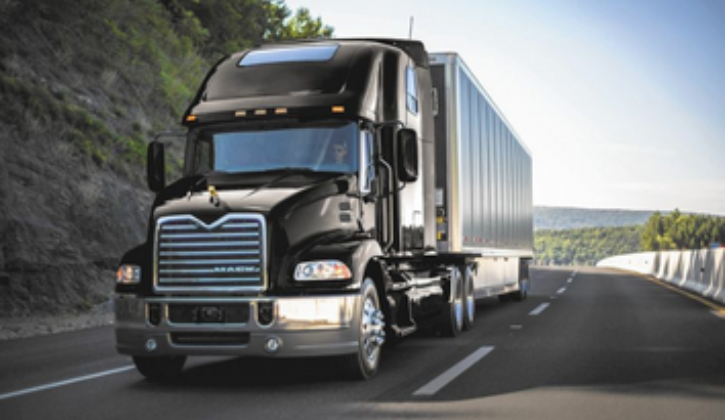 black semi truck on a curved road in smokey mountains