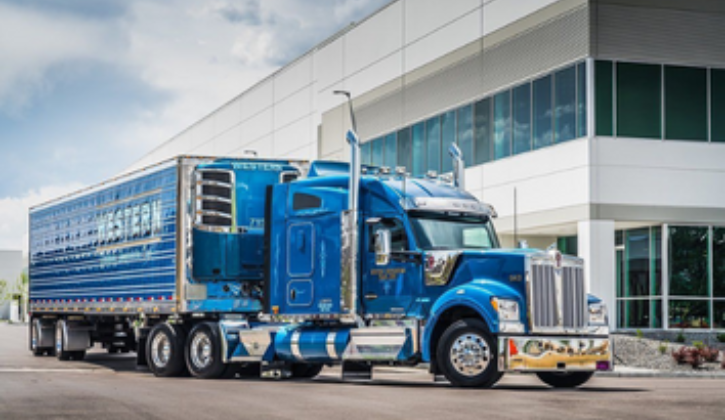 Blue semi truck and trailer in front of a building