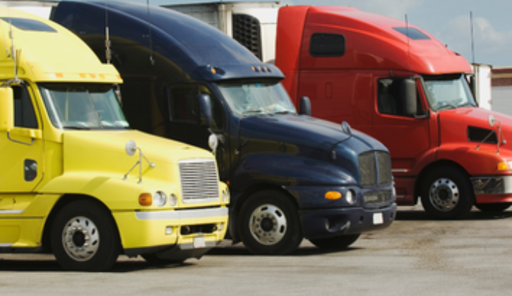 3 semi trucks sitting next to each other going from yellow, black, red.